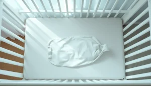 Minimalistyczne wyposażenie łóżeczka dla noworodka z twardym materacem i śpiworkiem.